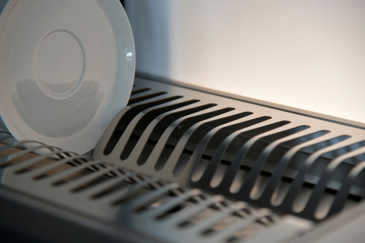 Services-02 Elegant ceramic plate on a sleek metal dish rack in a modern kitchen setting.